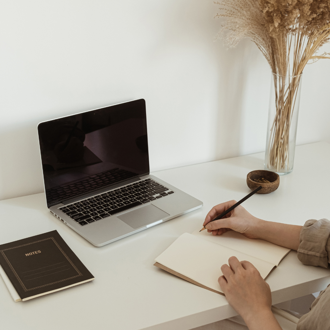 Functional medicine consult, hands writing in notebook in front of computer
