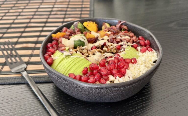 a black bowl full of brightly colored food on a black table next to a fork